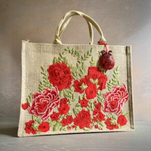 Red floral jute gift bag with embroidered garden flowers and ladybird charm – Pomme d’Or.