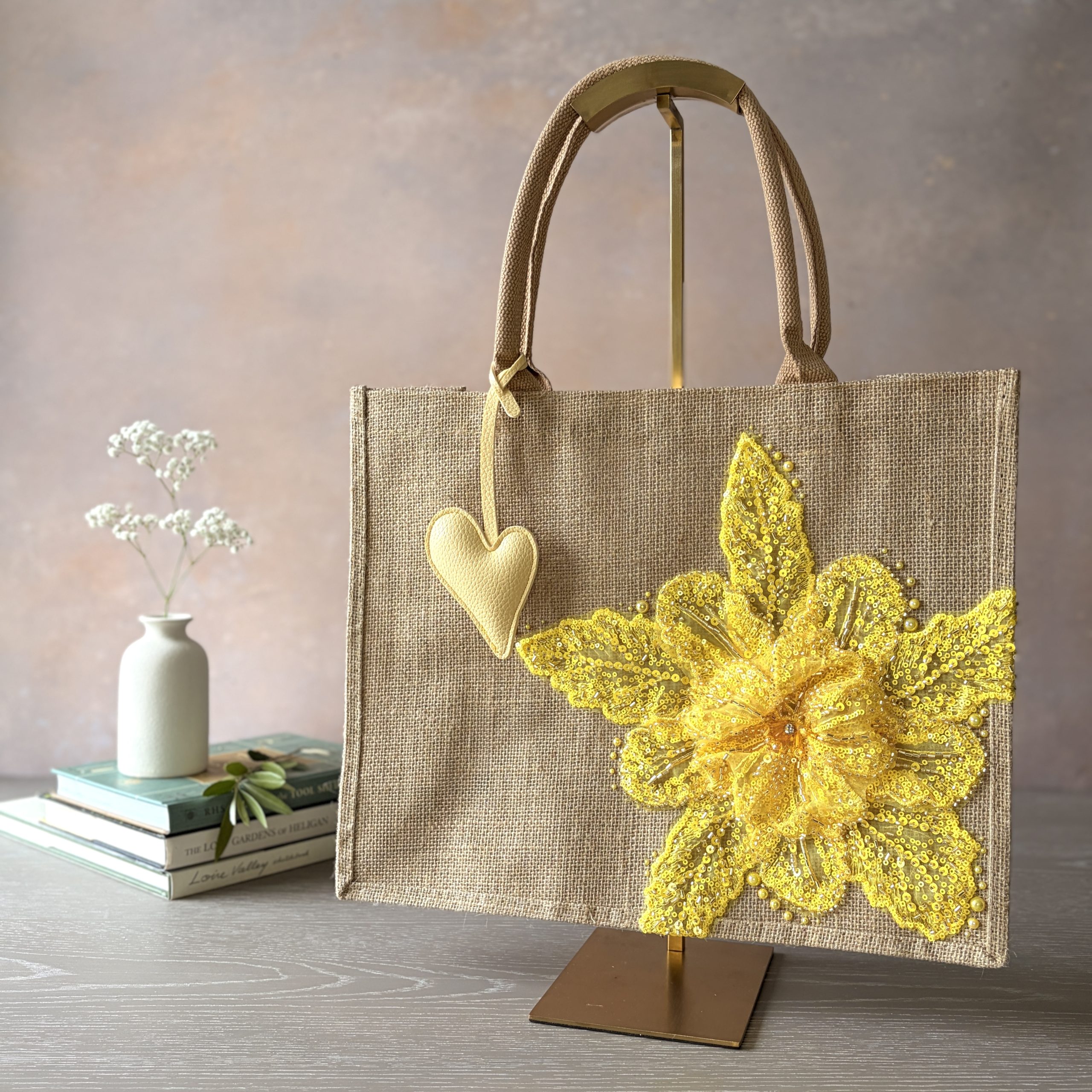 Yellow floral jute gift bag with bright sequin flower embellishment and heart charm – Pomme d’Or.