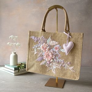 Blush floral jute gift bag with pastel embroidered flowers, bead detailing and heart charm – Pomme d’Or.