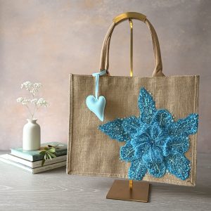 Turquoise floral jute gift bag with sequin flower embellishment and heart charm – Pomme d’Or.