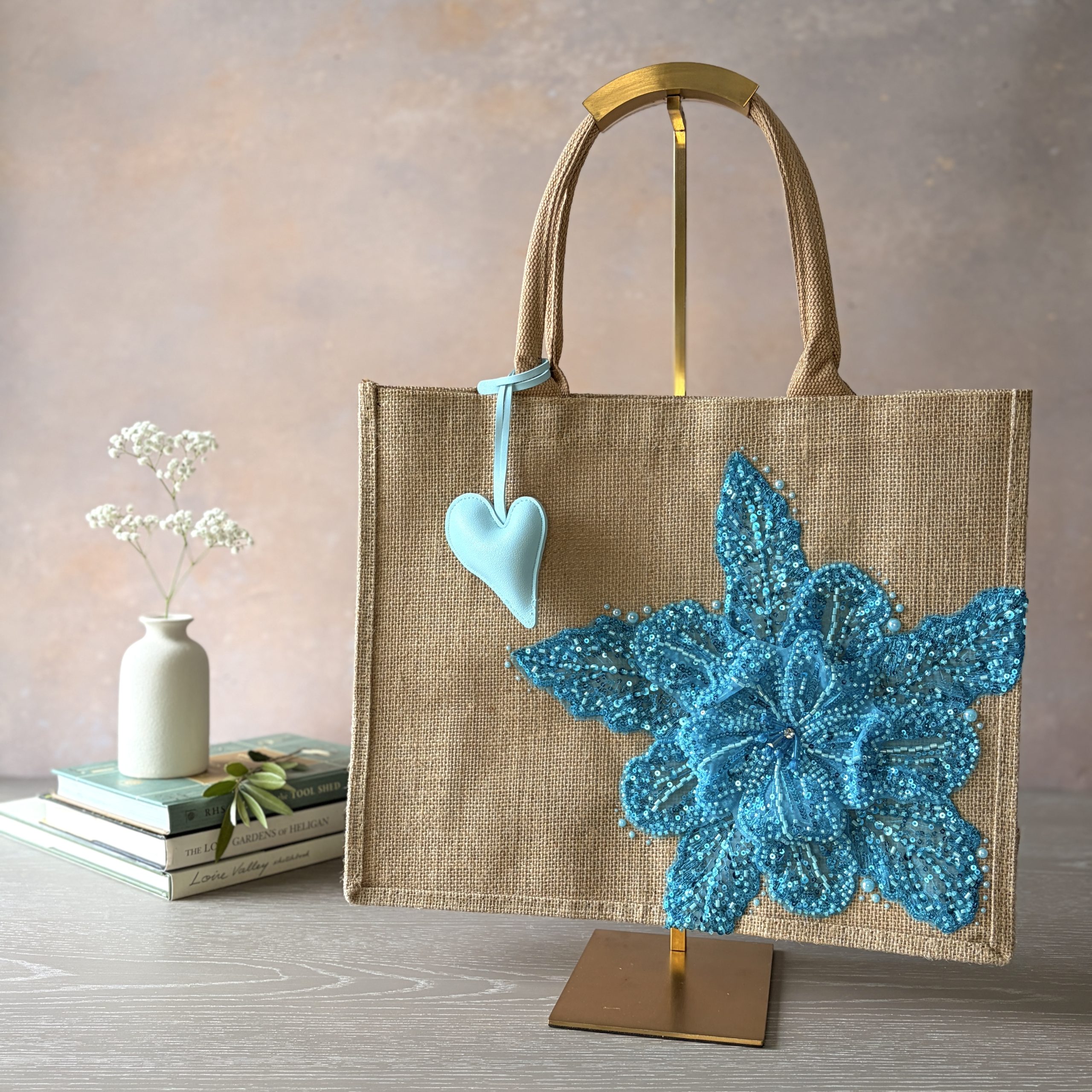 Turquoise floral jute gift bag with sequin flower embellishment and heart charm – Pomme d’Or.