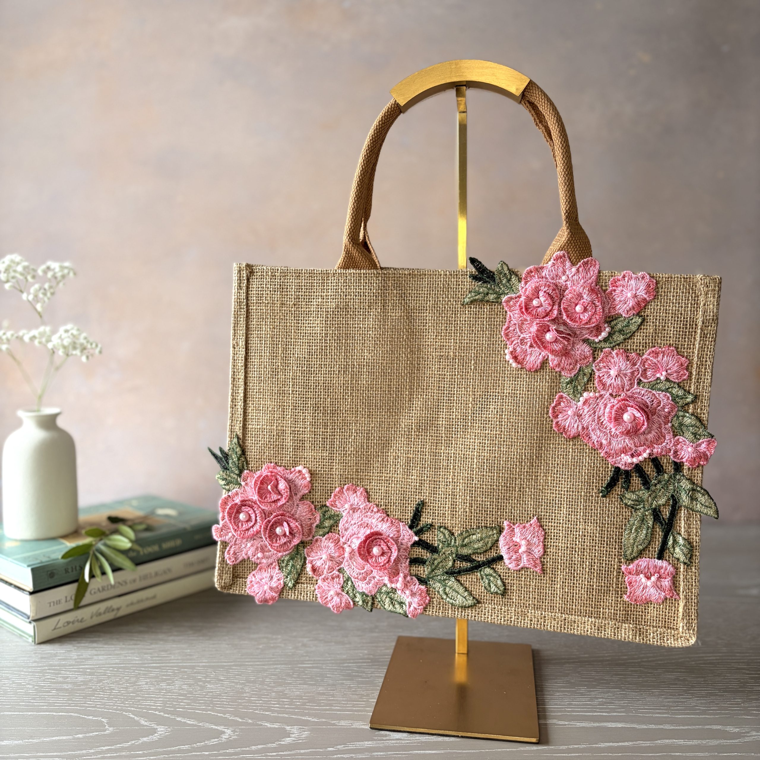 Pink floral jute bag with embroidered flowers, green leaves and pearl detailing, hand embellished by Pomme d’Or.