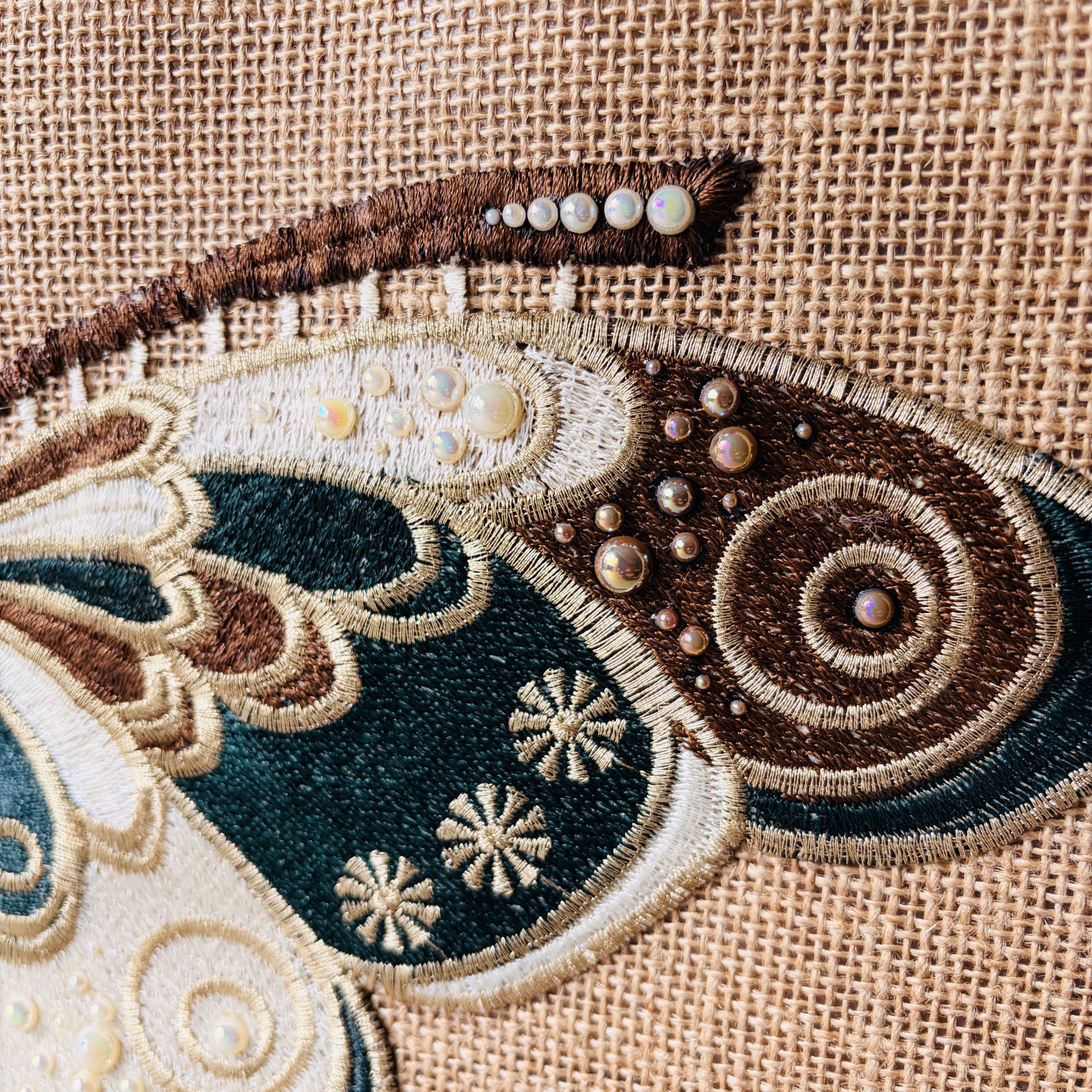 Close-up of embroidered butterfly wing and pearlescent bead detailing on Sylvan jute bag.