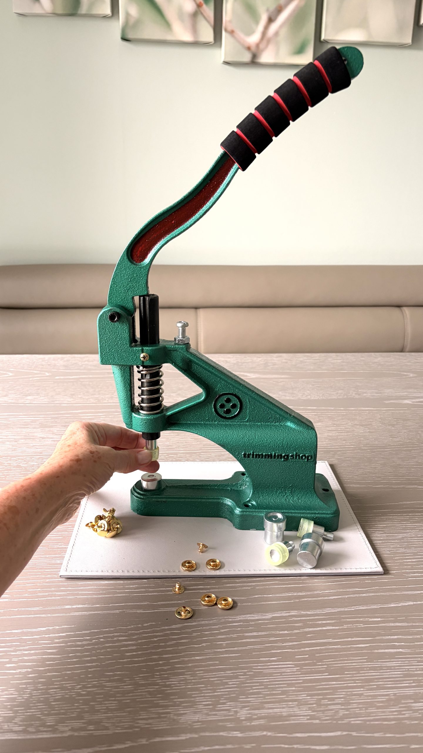 Anne-Marie using a Green Machine hand press to fit gold bag hardware in the Pomme d’Or studio